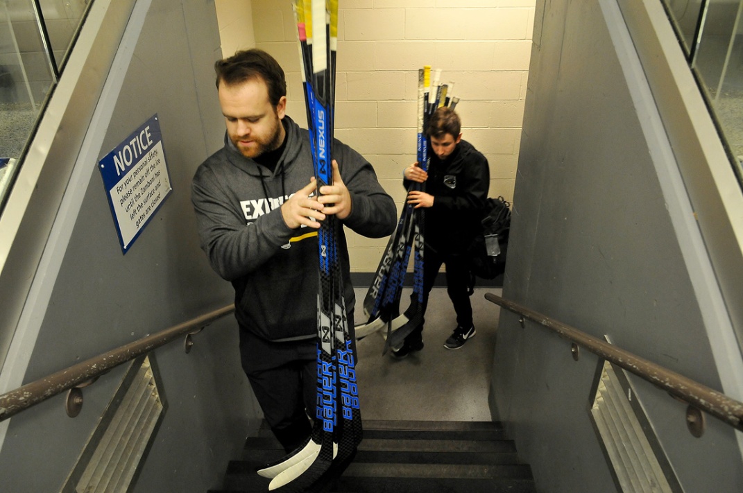 MARIO BARTEL/THE TRI-CITY NEWS Team chiropractor Harrison Wagner and trainer Russ Maceluch deliver the players' sticks to the bench.