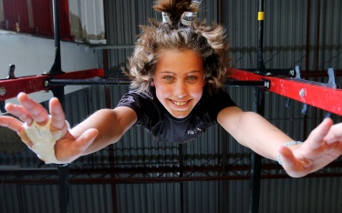 MARIO BARTEL/THE TRI-CITY NEWS Danika Michelsen hangs from a high bar at the Momentum Ninja Training Centre in Port Coquitlam. She's one of 36 athletes from the gym who've qualified to compete at the Ultimate Ninja Athletic Association world championships in Minnesota in July. This local Ninja gym is chock-a-block with climbing walls and other apparatus that can quickly overwhelm a photographer, let alone create busy backgrounds. That's when it's best to keep things simple.