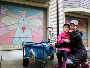 MARIO BARTEL/THE TRI-CITY NEWS Ladawne Shelstad and her daughter, Maddyn, 6, show off two of the chalk murals they designed and coloured on garage doors in their Klahanie neighbourhood to help brighten spirits during the COVID-19 lockdown. Their effort also inspired other neighbours to commission murals or design their own for their garage doors so now there's more than a dozen completed.